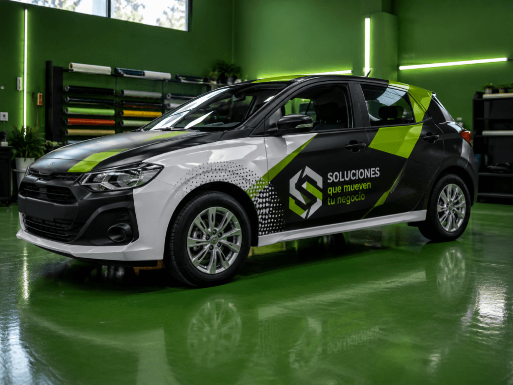 Vehículo con rotulado adhesivo personalizado en negro, blanco y verde dentro de un taller gráfico.